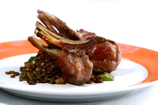 Costeleta de cordeiro grelhada com salada de lentilhas, espinafre e bacon