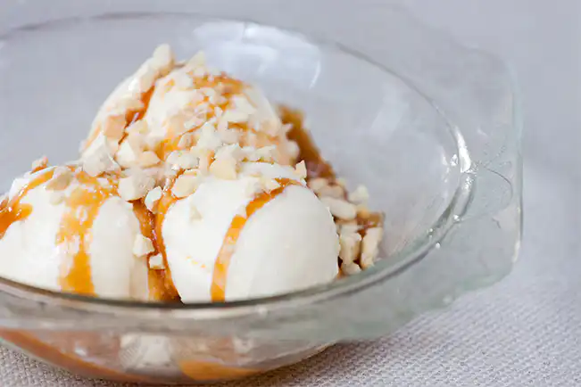 Sorvete de creme com raspas de laranja e calda de caramelo